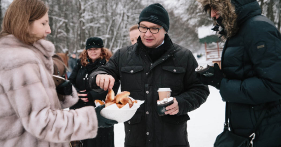 group in coats sharing coffee and bagels on winter day